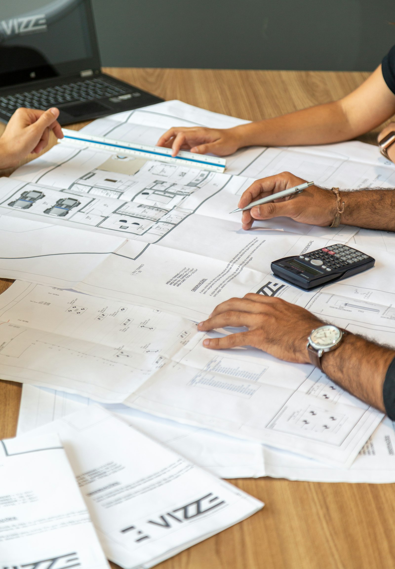 Estimators reviewing blueprints with a calculator and ruler